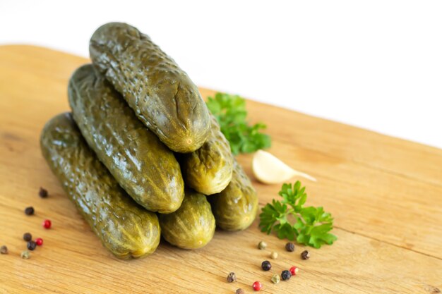 Pepinos en escabeche o fermentados sobre tablero de madera aislado en blanco