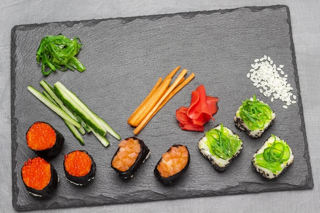 Pepinos en rodajas de sushi y algas de zanahorias en tablero de piedra
