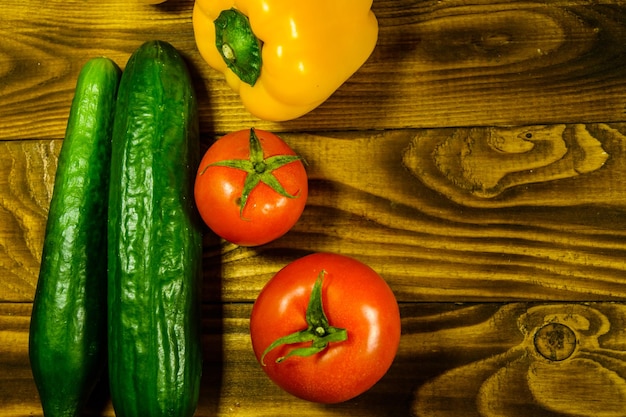 Pepinos, tomates e pimenta doce em uma mesa de madeira