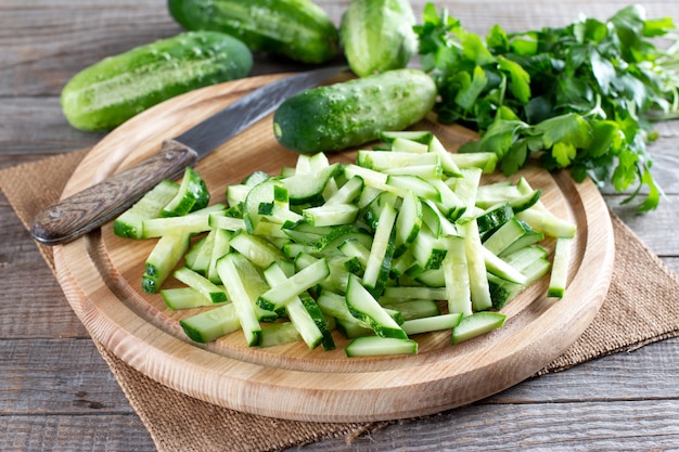 Pepinos verdes fatiados frescos em uma placa de corte em uma mesa de madeira. Ingrediente vegetariano saudável