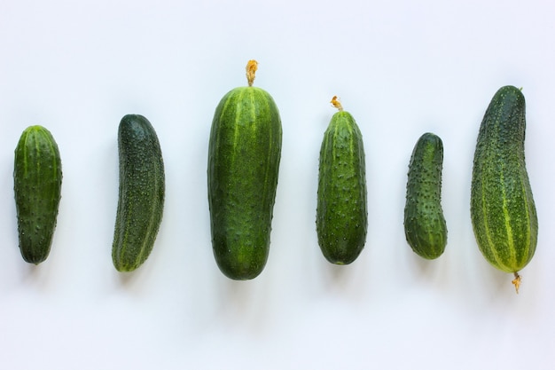 Pepinos verdes en una fila sobre un fondo claro, directamente desde arriba. comida, verduras en la mesa. endecha plana.