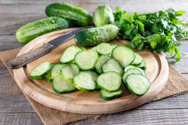 Pepinos verdes en rodajas frescas sobre una tabla para cortar sobre una mesa de madera. Ingrediente vegetariano saludable