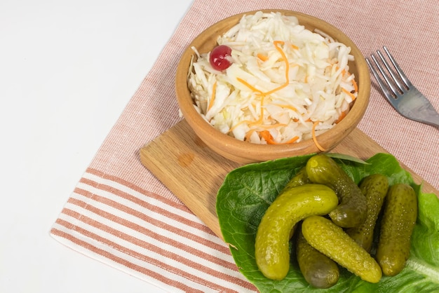 Pepinos de verduras en escabeche con chucrut en un plato en la vista de fondo de la mesa