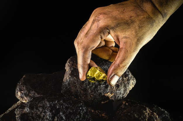 Pepita de ouro na mão de um mineiro, pedra de ouro escondida