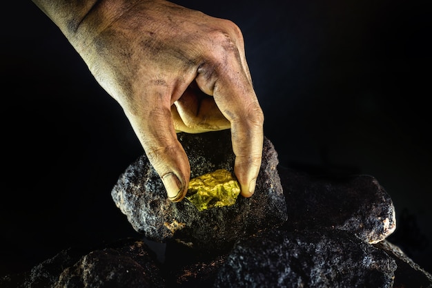 Pepita de ouro na mão de um mineiro, pedra de ouro escondida