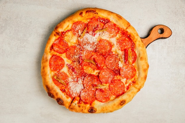 Foto pepperoni-pizza mit chili-pfeffer auf einem holzbrett, draufsicht