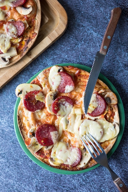 Foto pepperoni-pizza mit mozzarella-käse, weißem pilz und sriracha