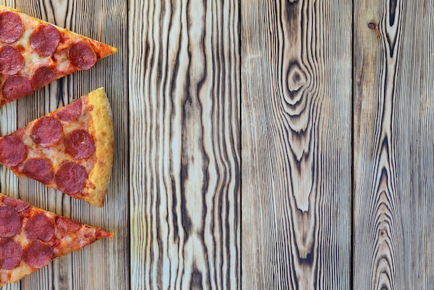 Pepperoni-Pizza mit Spinat auf einem hölzernen Hintergrund