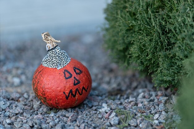 Pequena abóbora laranja decorada para o halloween um rosto foi desenhado e uma tampa preta e branca foi feita