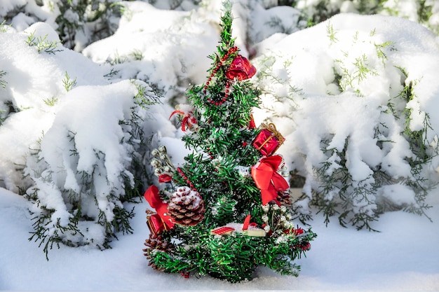 pequena árvore de Natal com brinquedos e cones em uma floresta de neve