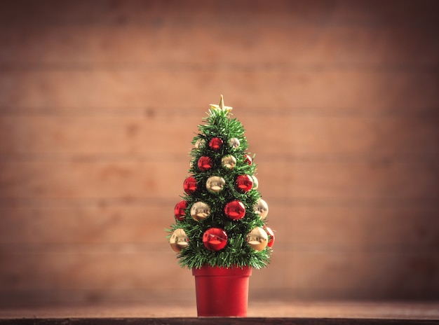 Pequena árvore de Natal na mesa de madeira e fundo