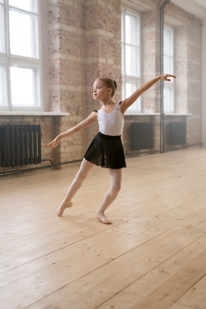 Pequeña bailarina aprendiendo a bailar durante el entrenamiento de ballet en el estudio