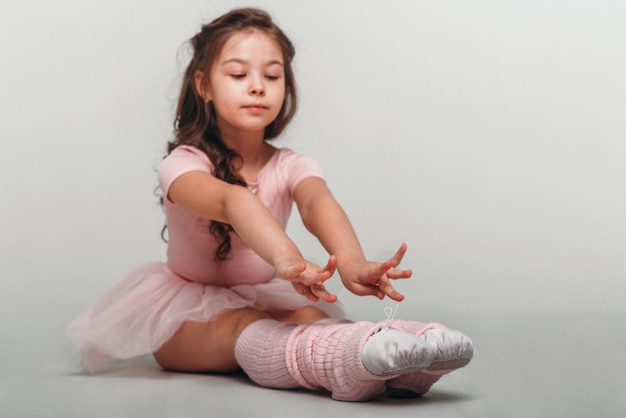 Pequeña bailarina bailarina en un estudiante de la academia de tutú rosa posando sobre fondo blanco