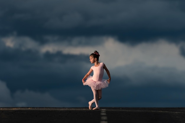 Pequeña bailarina de ballet con un tutú rosa en el horizonte de la carretera a la hora dorada