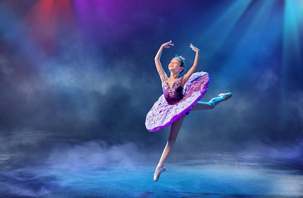 Una pequeña bailarina japonesa baila en el escenario con un tutú lila en zapatos de punta ballet clásico