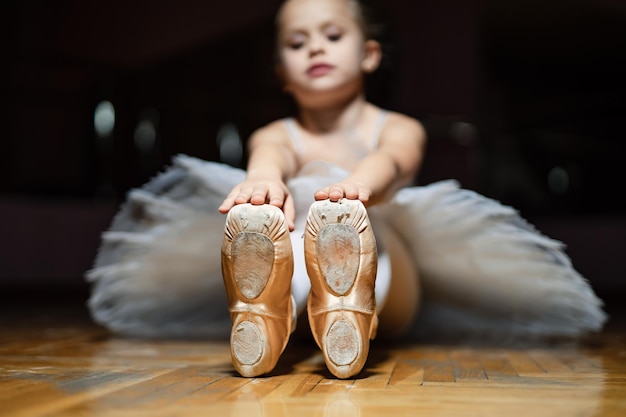 Pequeña bailarina sueña una bailarina delicada con pies elegantes una niña pequeña sentada en el suelo con un par de zapatos de ballet