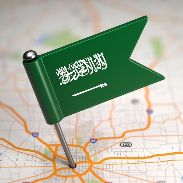 Pequeña bandera de Arabia Saudita sobre un fondo de mapa con enfoque selectivo.