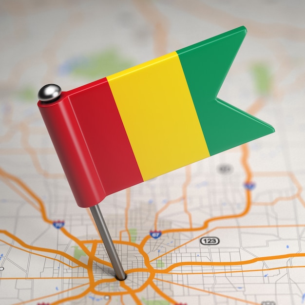 Pequeña bandera de la República de Guinea sobre un fondo de mapa con enfoque selectivo.