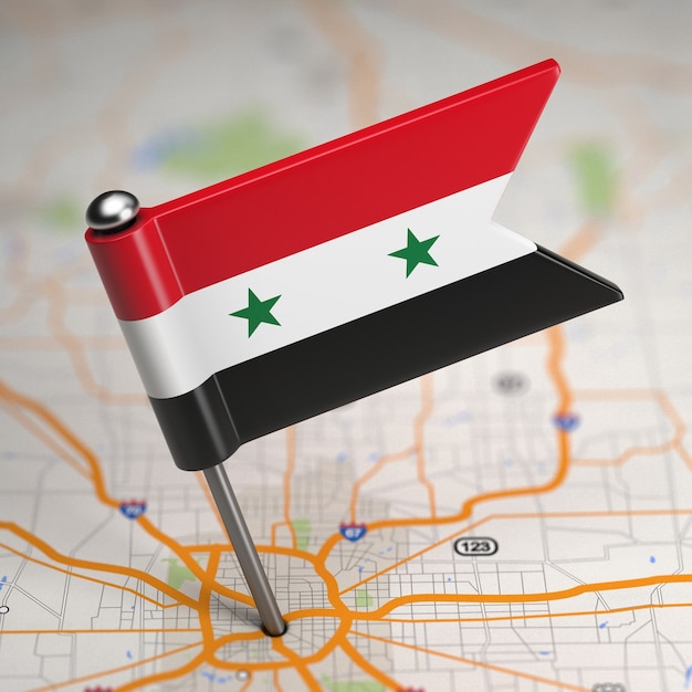 Pequeña bandera de la República Árabe Siria sobre un fondo de mapa con enfoque selectivo.