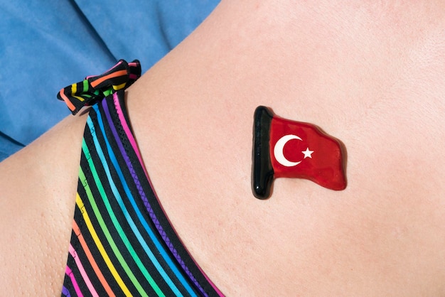 Pequeña bandera turca de cerámica brillante se encuentra en el estómago de una mujer en traje de baño