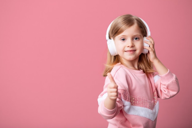 Una pequeña blogger escucha música con auriculares blancos
