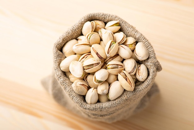 Pequeña bolsa de lino con pistachos sobre mesa de madera