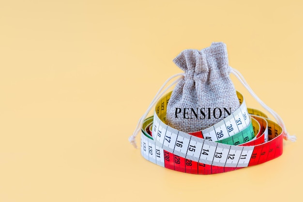 Una pequeña bolsa de lona con la palabra PENSIÓN envuelta con un centímetro sobre un fondo amarillo