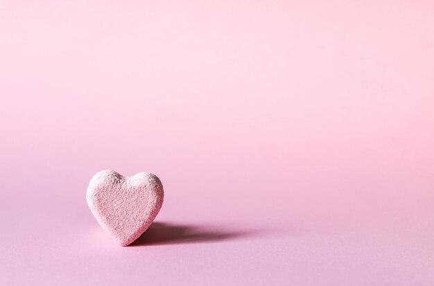 Pequeña bomba de baño rosa en forma de corazón sobre fondo pastel suave