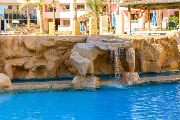 Pequena cachoeira com água turquesa na piscina do hotel
