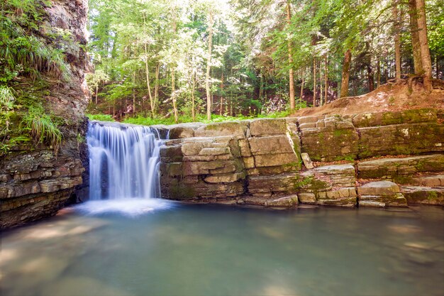 Pequena cachoeira na floresta de montanha com água de espuma sedosa