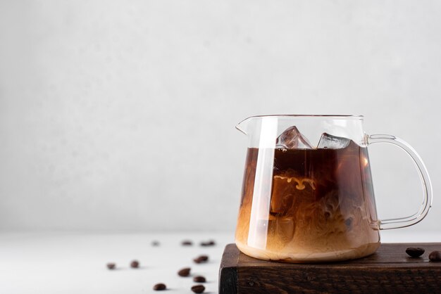 Pequeña cafetera con café helado y leche sobre un fondo claro, primer plano