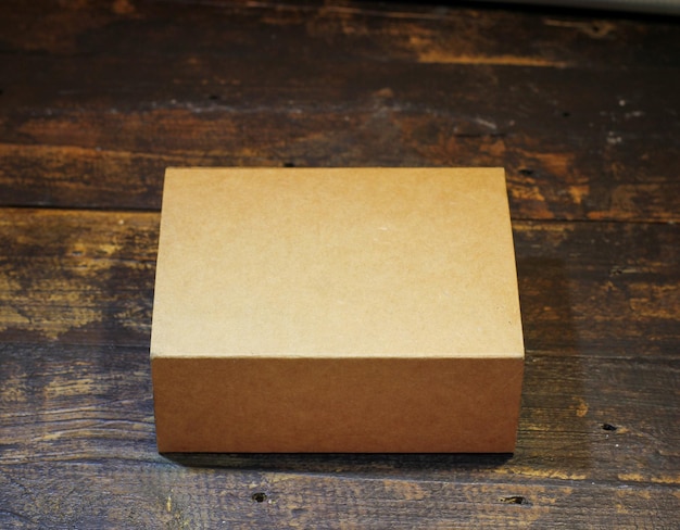 Pequeña caja de cartón en blanco sobre fondo de madera