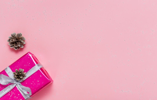 Foto pequeña caja de regalo rosa con cinta de plata sobre el fondo rosa claro. endecha plana. copia espacio