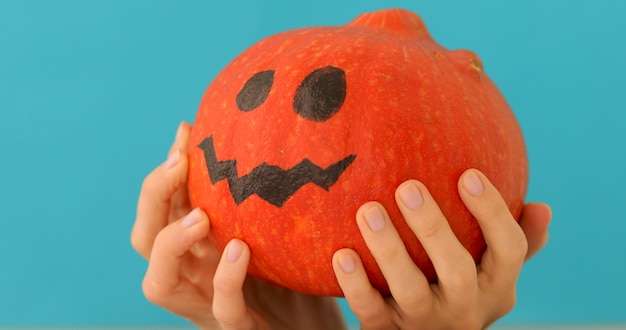 Pequeña calabaza naranja piensa sobre fondo azul.