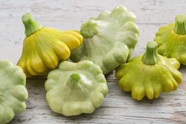 Pequeña calabaza pattypan temprana sobre tabla de madera.