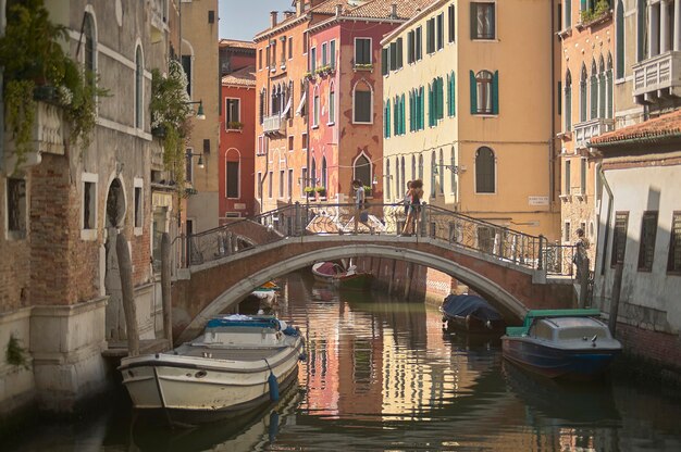 Pequeña calle de Venecia con edificios históricos que dan directamente a un pequeño arroyo y unidos por un puente.
