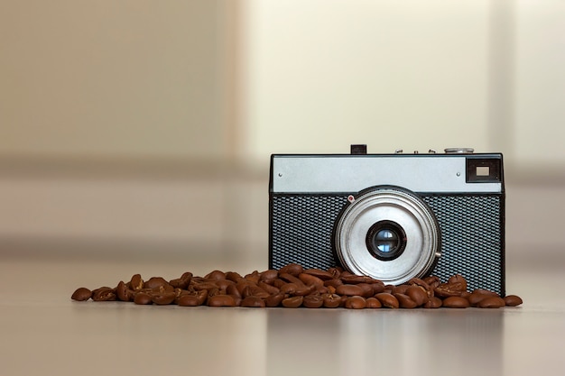 Pequeña cámara vintage antigua y granos de café en borrosa