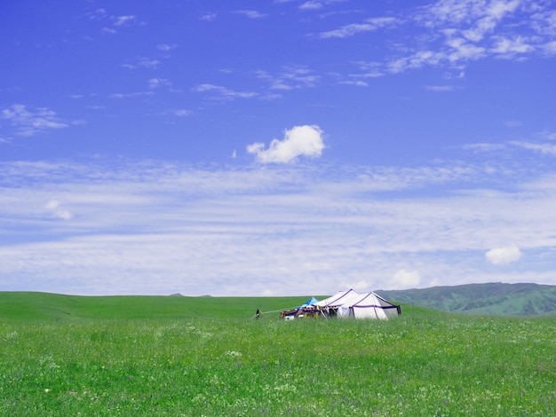 Pequeña casa en el campo de hierba en el valle y el cielo azul.