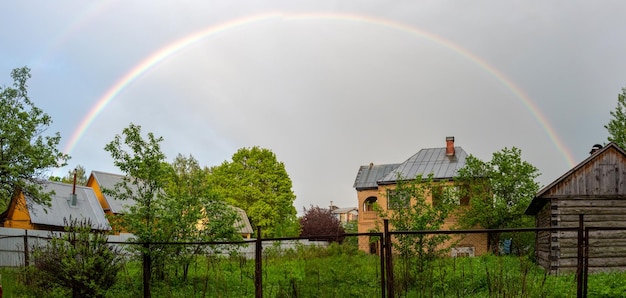 Pequeña casa de campo en una tarde de verano Arco iris sobre la casa Hermosa puesta de sol Flores en el jardín Rusia