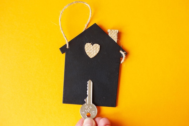 Pequeña casa de juguete con una llave sobre un fondo naranja.