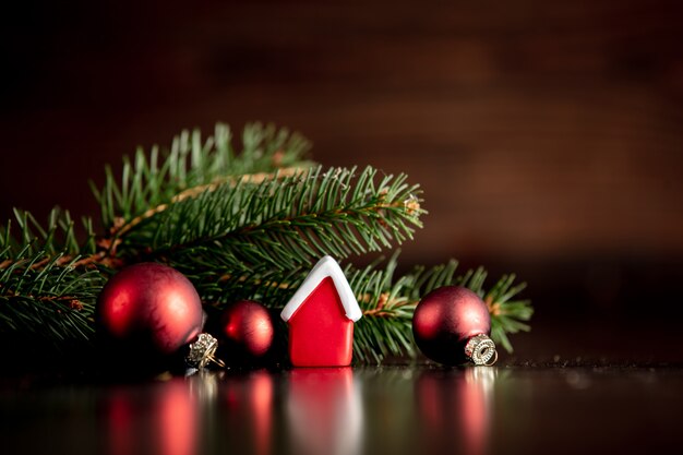 Pequeña casa de juguete y rama de árbol de Navidad