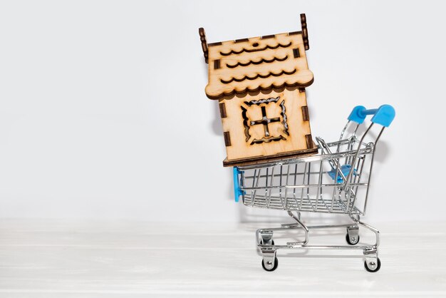 Pequeña casa de madera en un carrito de compras con espacio de copia