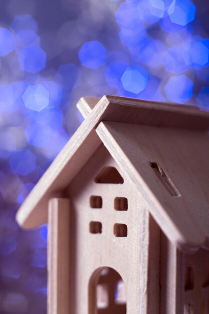 Foto pequeña casa de madera contrachapada decorativa de cerca contra el fondo de las luces azules del bokeh