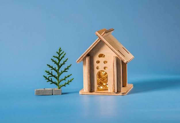 pequeña casa de madera hecha en casa con una guirnalda dentro y un árbol de Navidad