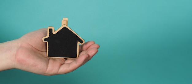 La pequeña casa de madera en las manos representa conceptos como el cuidado del hogar, el amor familiar