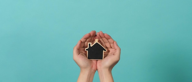 La pequeña casa de madera en las manos representa conceptos como el cuidado del hogar, el amor familiar