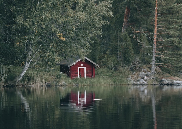 Pequeña casa de madera roja en la orilla de un lago en Finlandia