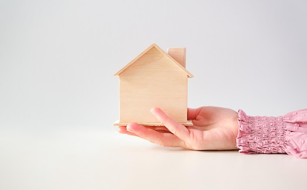 Pequeña casa en mano femenina aislada en blanco