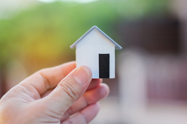 Pequeña casa modelo en manos de hombres.