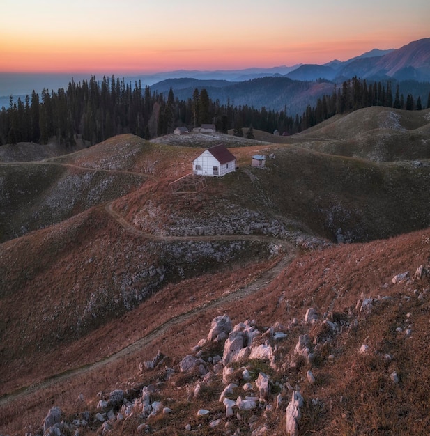 Pequena casa nas montanhas ao pôr do sol no outono